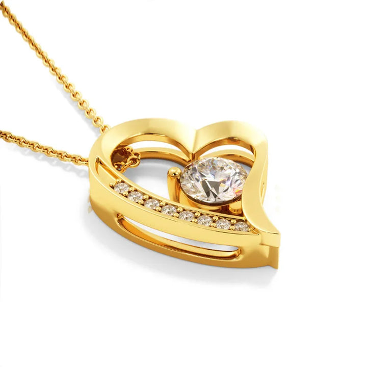 Gold heart-shaped pendant with a diamond on a white background