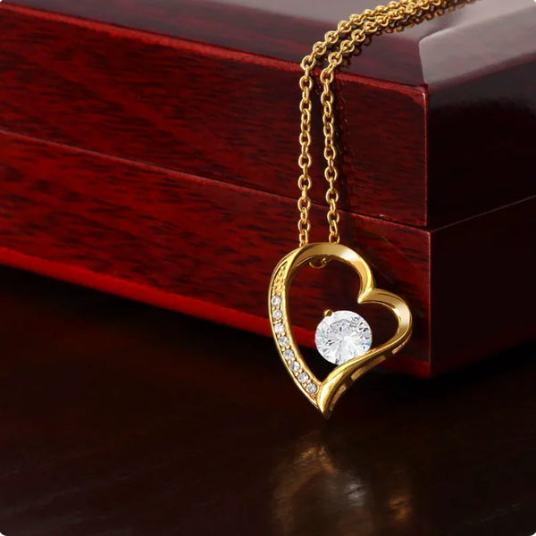 Gold heart-shaped necklace with a diamond pendant on a wooden surface