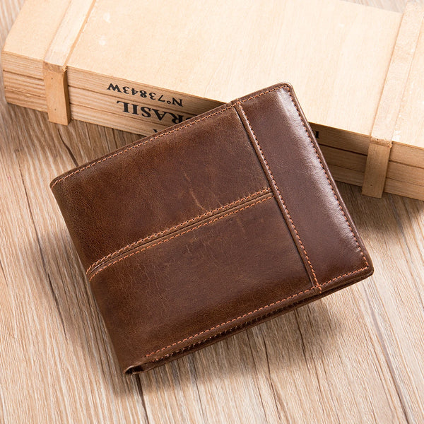 Brown leather wallet on a wooden surface with a wooden box in the background