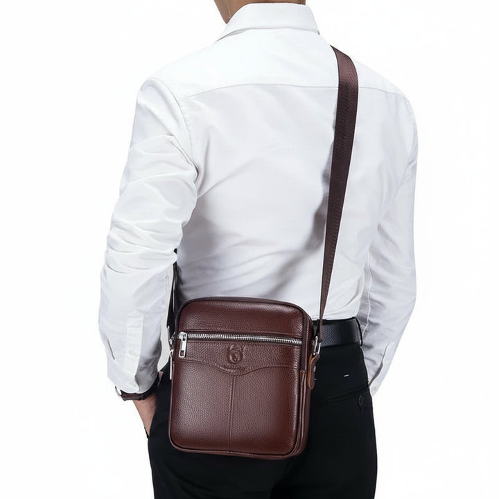 Man wearing a brown leather crossbody bag with a plain background, featuring the Bullcaptain brand.