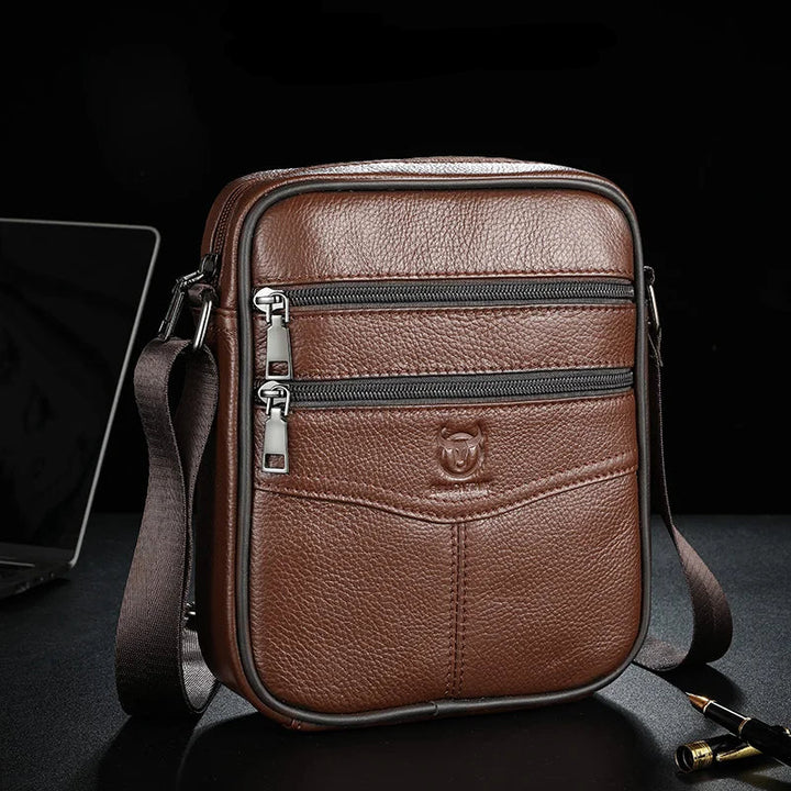 Brown leather crossbody bag with visible Bull Captain logo on a dark background