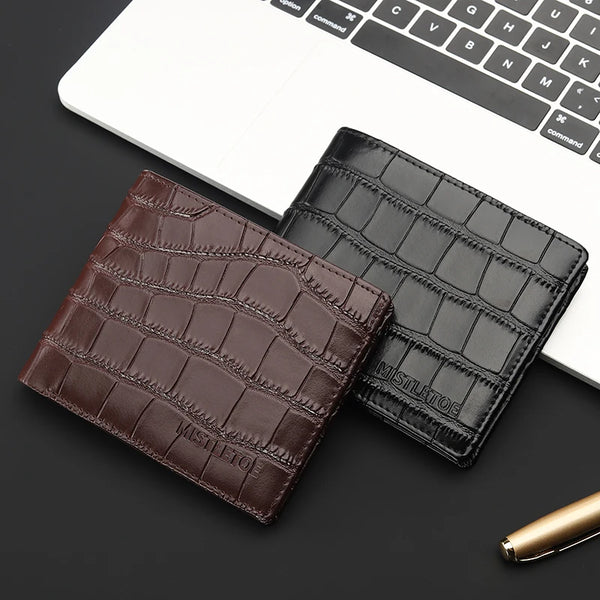 Two leather card holders, one brown and one black, on a dark surface with a laptop in the background.