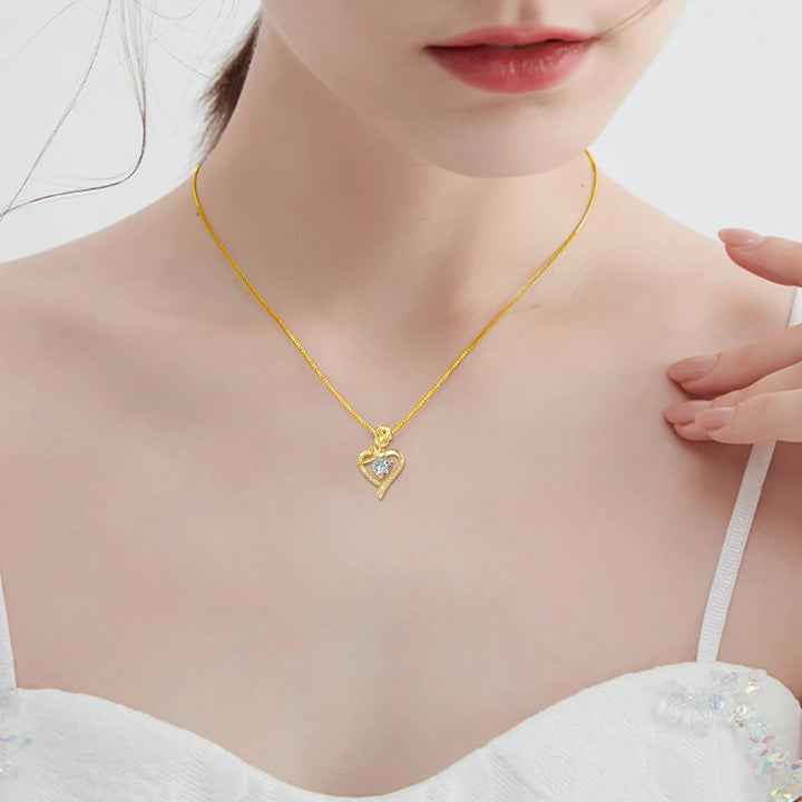 Gold necklace with a heart-shaped pendant worn by a model against a white background